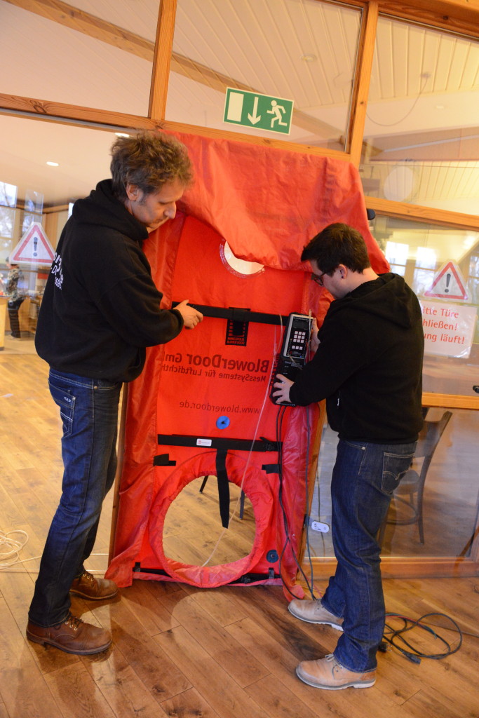 Referent Holger Merkel (links) mit Architekt Dennis Krupp: Die Teilnehmer lernen beim BlowerDoor- Basisseminar, wie das Equipment auf- und abgebaut wird. 
