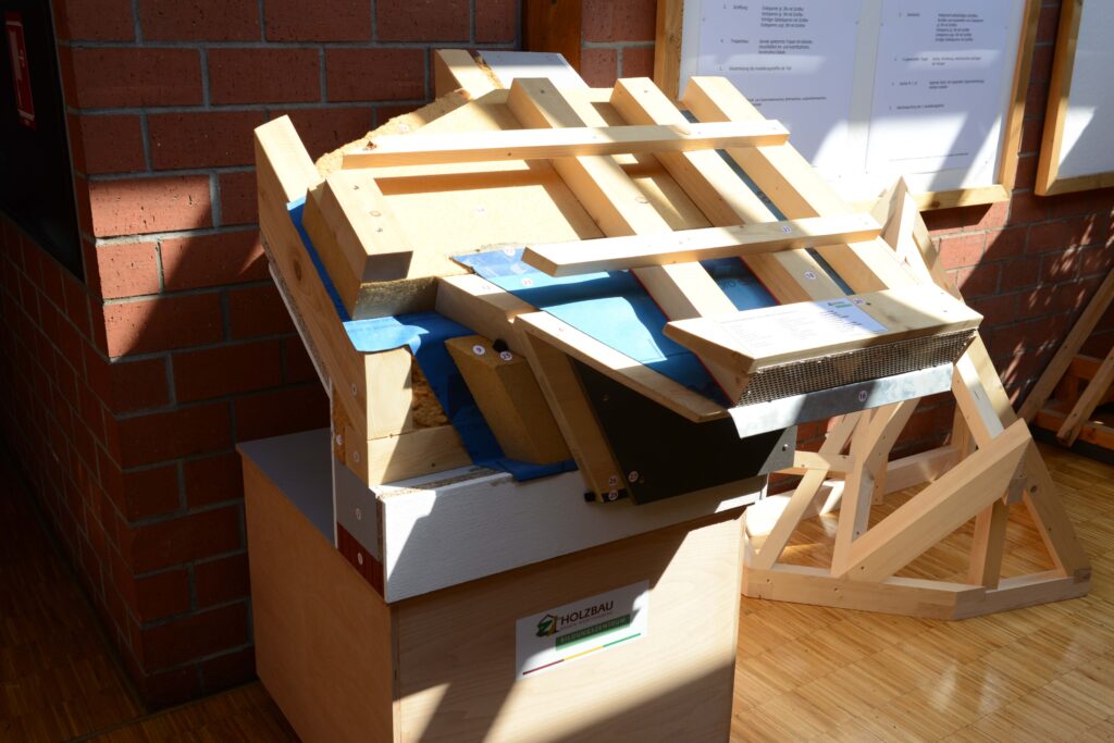 Dachsanierungs-Eckmodell des Bildungszentrums Holzbau in Biberach: Das dreidimensional angeordnete Modell weist vor allem auf die Anschlusssituation zwischen Traufe und Ortgang. Als Beispiel wird hier gezeigt, wie die luftdichte Ebene über den Sparren geführt wird, indem der Dachvorsprung vorher abgeschnittten wurde. „So kann die Gebäudehülle komplett eingepackt werden, ohne Durchbrüche“, sagt Zimmerermeister und Ausbilder Helmut Schuler. Der Dachvorsprung wird später an die Konterlatten gehängt. 